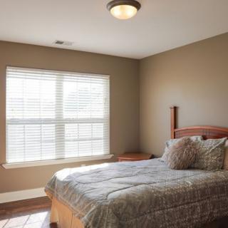 A minimalist bedroom with natural light streaming through a large window.