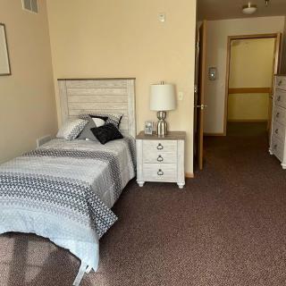 A cozy bedroom with a single bed, nightstand, and dresser in a neatly arranged space.