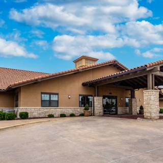 A modern building with a stone facade and a welcoming entrance under a partly cloudy sky.