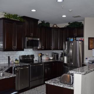 A modern kitchen with dark cabinets and stainless steel appliances.