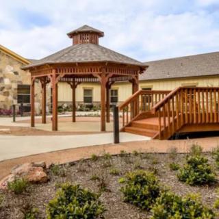 A landscaped outdoor area featuring a wooden gazebo and adjacent building.