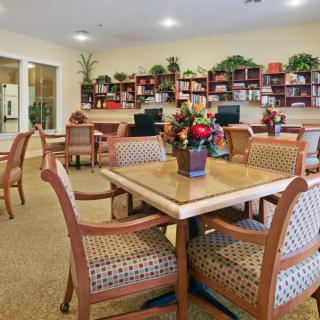 A comfortable community library setting with tables, chairs, and bookshelves filled with books.