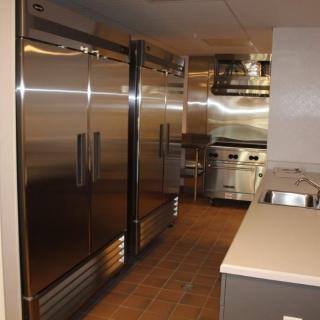 A commercial kitchen featuring stainless steel appliances, including refrigerators and cooking equipment.