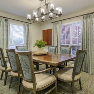 A well-appointed dining room featuring a large wooden table, upholstered chairs, and an elegant chandelier.
