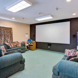 A cozy home theater room with comfortable sofas and a large projector screen.