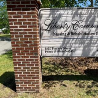 A sign for Liberty Community Nursing & Rehabilitation Center, mounted on a brick column.