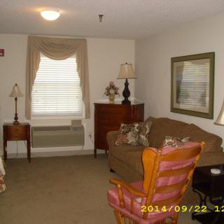 A cozy living room with a sofa, chairs, lamps, and a window with curtains.