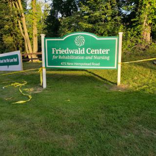 Sign of the Friedhold Center surrounded by greenery.