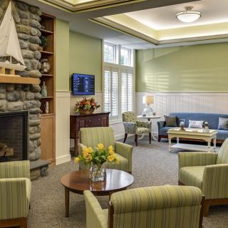 A cozy living room with modern decor, featuring a stone fireplace, comfortable seating, and green walls.