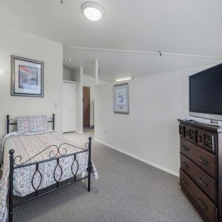 A cozy bedroom with a single bed, dresser, and television.