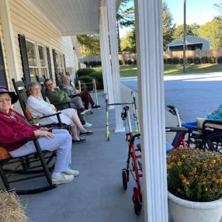 A group of seniors enjoying their time together on a porch, basking in the sunshine.