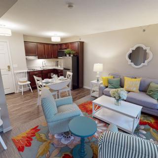 A modern apartment with a vibrant living room and kitchen area, featuring colorful furniture and decor.