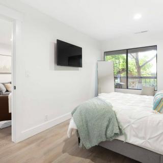 A modern, minimalist bedroom with a wall-mounted TV and large window.