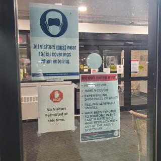 Health and safety guidelines displayed at the building entrance.