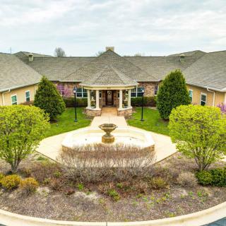 Aerial view of a luxurious mansion with a well-maintained garden and centerpiece fountain.
