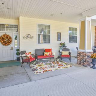 A cozy porch with seating and decorative elements creates a welcoming atmosphere.