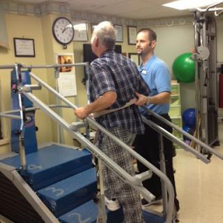 A physical therapist assisting an elderly patient in a rehabilitation setting, focusing on stair climbing.