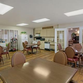 A cozy dining area with multiple tables and chairs, featuring a small kitchen setup in the background.