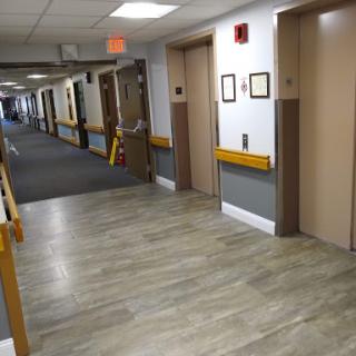 A view of a hospital hallway featuring elevators and patient rooms.