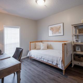 A cozy room with a daybed, desk, and bookshelf, perfect for a tranquil home office setup.