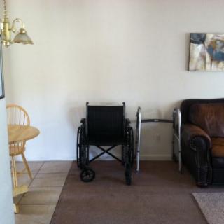 A living room area featuring a wheelchair, walker, and furniture.