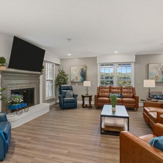A modern living room with comfortable seating and a large television above the fireplace.