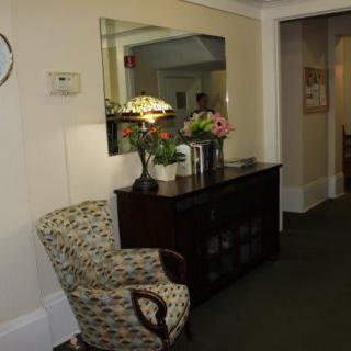 A cozy living area with a patterned chair, sideboard, and decorative mirror.