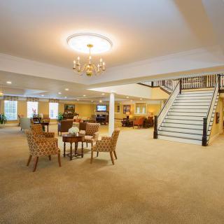 A spacious lobby with a chandelier, seating area, and ascending staircase.