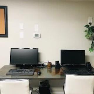 A minimalist office setup with two computers and chairs at a shared desk.