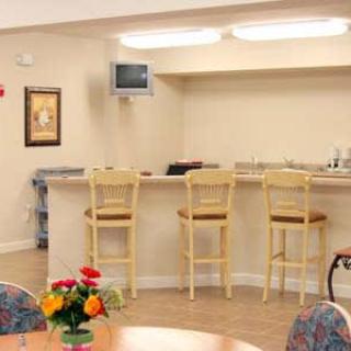A cozy interior with a bar area, featuring wooden stools, a small TV, and a table with vibrant flowers.