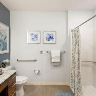 A modern bathroom with a shower, artwork, and neatly arranged towels.