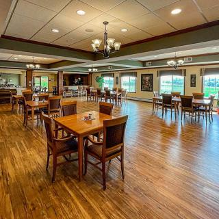 Spacious dining room with wooden floors and neatly arranged tables and chairs.