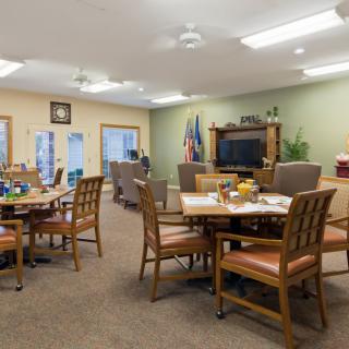 A cozy communal living and dining area with tables, chairs, and a television.