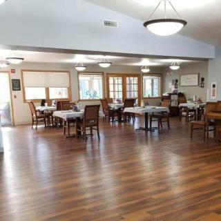 An empty dining room with tables and chairs on a wooden floor.