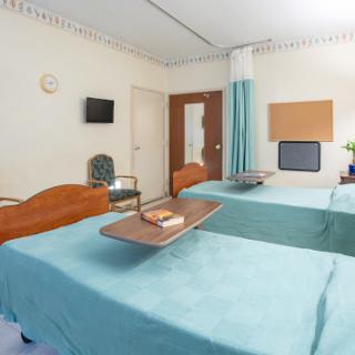 A hospital room featuring two beds with a tray table, equipped for patient care.