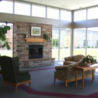 A cozy living room with a stone fireplace, comfortable seating, and large windows allowing natural light.