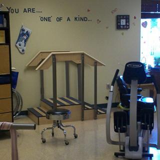A rehabilitation room equipped with exercise machines and an inspirational wall quote.