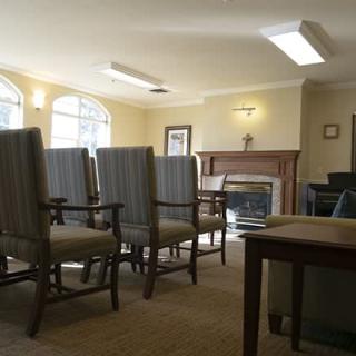 A well-lit meeting room with several chairs facing a fireplace.