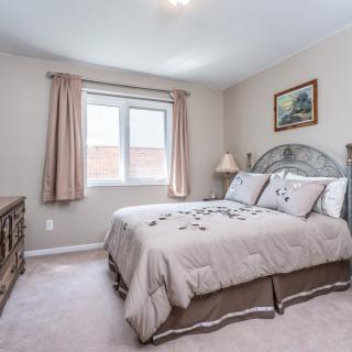 A cozy bedroom with a bed, curtains, and soft lighting.