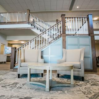 A stylish lobby featuring two armchairs and a table, set against a backdrop of an elegant staircase.