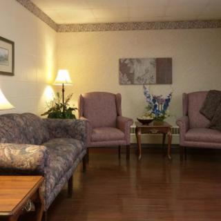A cozy living room with patterned armchairs, a sofa, and decorative elements like lamps and indoor plants.