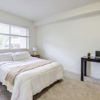 A minimalist bedroom with a cozy bed and a small desk.