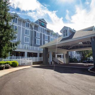 A hotel building with a driveway and entrance under a partly cloudy sky.