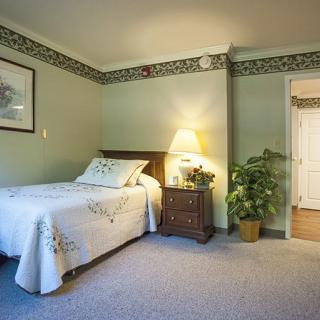 A cozy bedroom with a single bed, bedside lamp, and decorative accents.