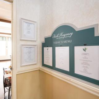 A restaurant interior featuring a wall-mounted menu and framed certificates.