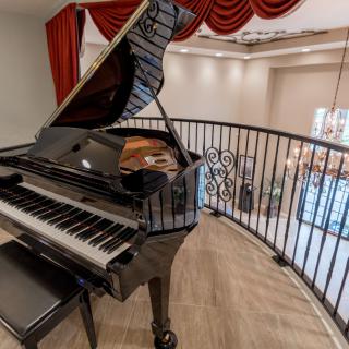 A grand piano elegantly placed on a balcony overlooking a stylish interior.