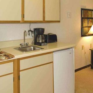 A small kitchen area featuring a coffee maker, sink, and microwave on the countertop.