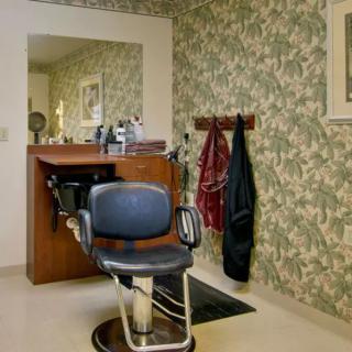 A cozy salon interior with a vintage barber chair and floral wallpaper.