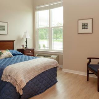 A cozy and well-lit bedroom featuring a comfortable bed, elegant furnishings, and a serene atmosphere.