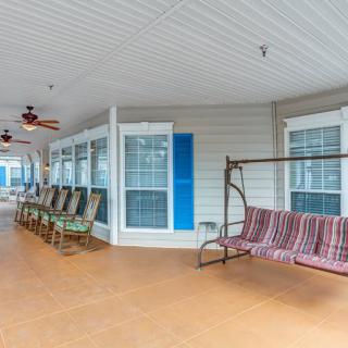A spacious porch featuring a swing, multiple rocking chairs, and ceiling fans for a relaxing outdoor experience.